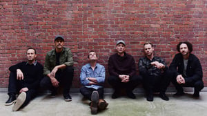 Umphrey's McGee seated casually in front of a brick wall